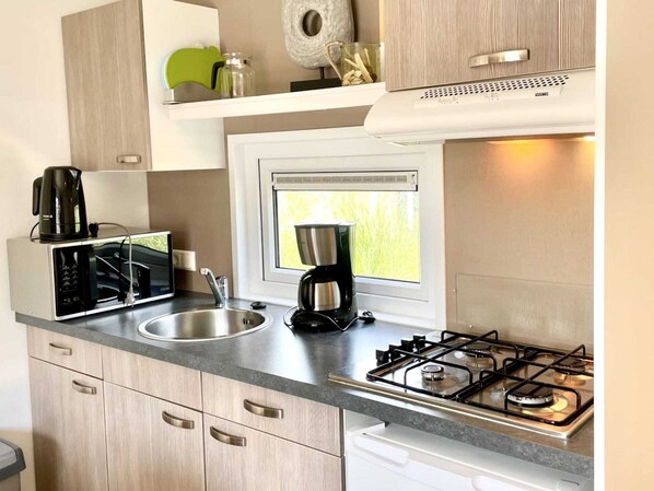 A modern kitchen with a gas stove, a microwave, a coffee maker, and a window above the sink.
