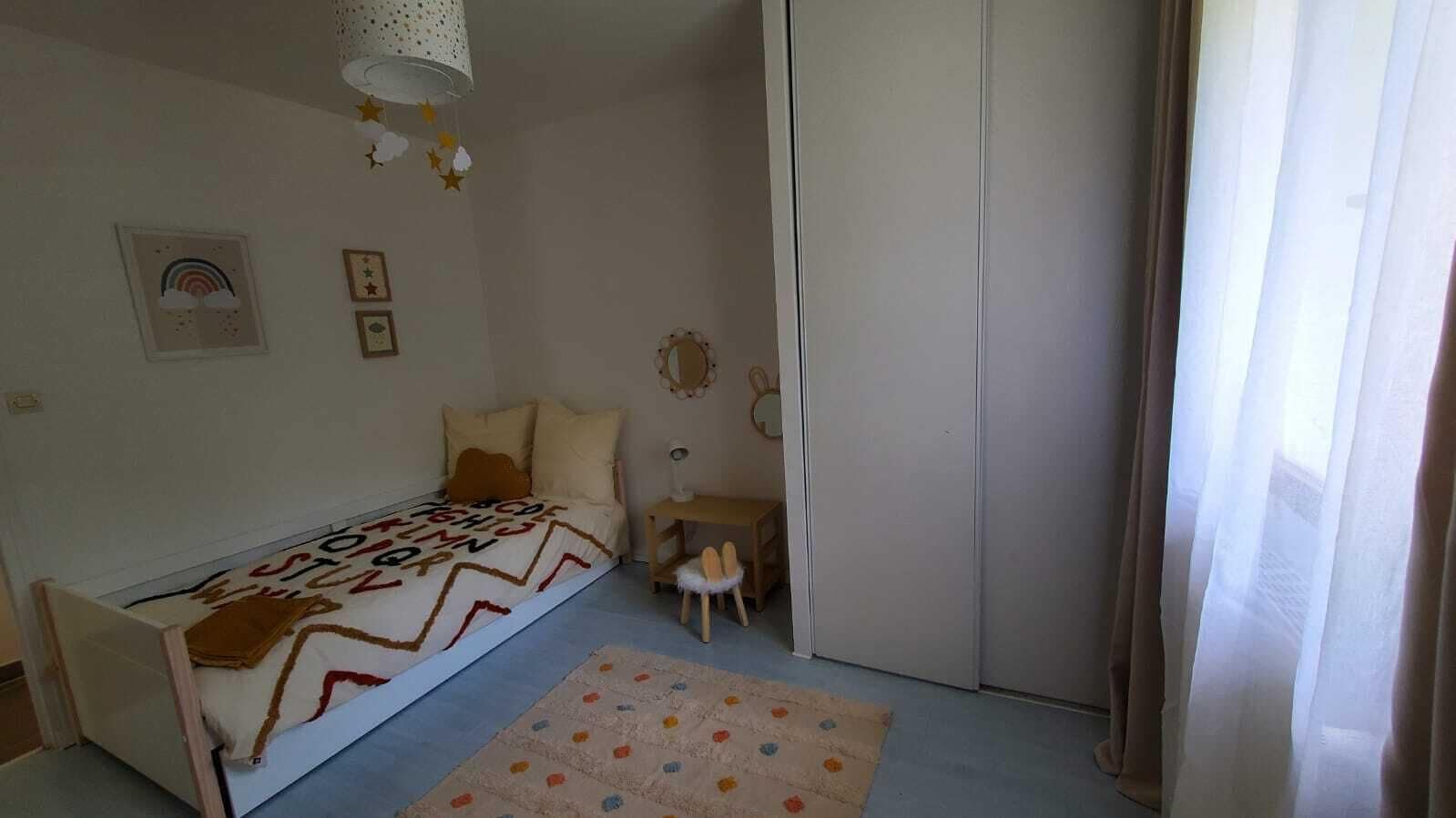 A bedroom with a single bed, a small table, a chair, and a wardrobe.