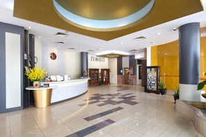 A hotel lobby with a reception desk, a clock, framed pictures, and a plant. - Kings Hotel (Malacca City)