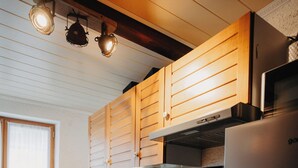 Une cuisine moderne avec des meubles en bois, un réfrigérateur en acier inoxydable, un four encastré et un plan de travail noir.