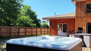 A wooden house with a hot tub and outdoor furniture on a wooden deck.
