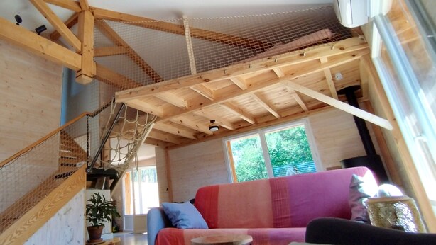 A wooden interior with a staircase, a window, and a pink sofa.