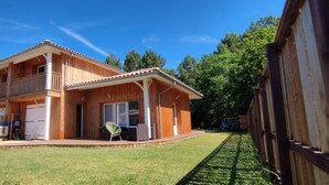 A two-story wooden house with a balcony, a garage, and a fenced backyard.