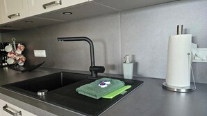 Une cuisine moderne avec un évier noir, une serviette verte et un distributeur de serviettes en papier.