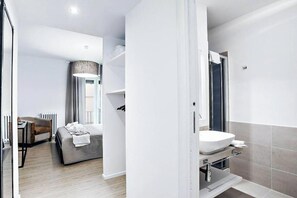 Une chambre d’hôtel moderne équipée d’un lit, d’un bureau et d’une salle de bain avec un lavabo et une douche.