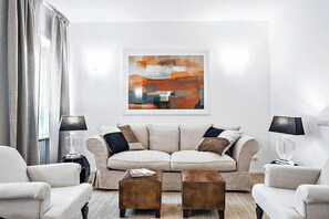 Un salon moderne avec un canapé beige, deux fauteuils et une table basse.