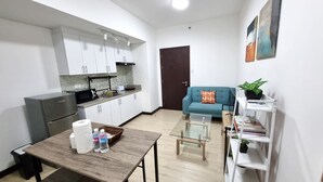 Un espacio habitable compacto con kitchenette, comedor, sofá y estantería.