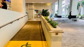 Rampa accesible para sillas de ruedas que conduce a la entrada de un edificio con fachada de vidrio.