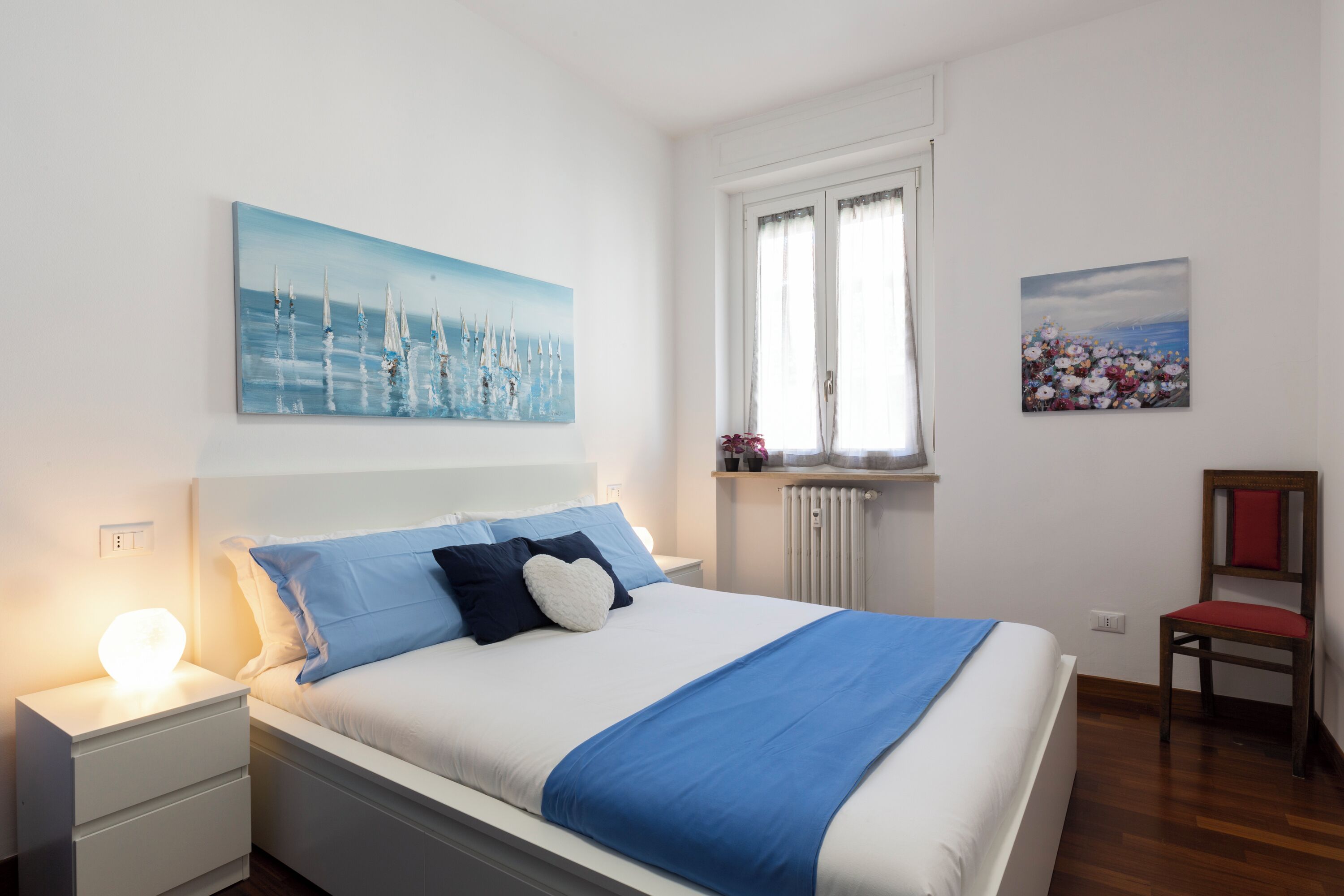 A neatly arranged bedroom with a bed, bedside table, and a chair.