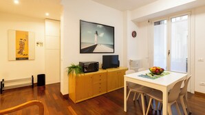 A modern dining area with a wooden cabinet, a television, and a table with chairs. - notaMi - Rainbow Home - CityLife (Milan)