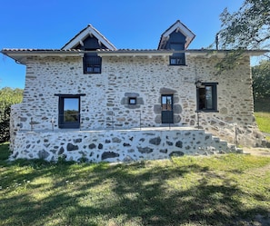 A stone building with a steep roof, multiple windows, and a small balcony. - Country house  (Vezac)