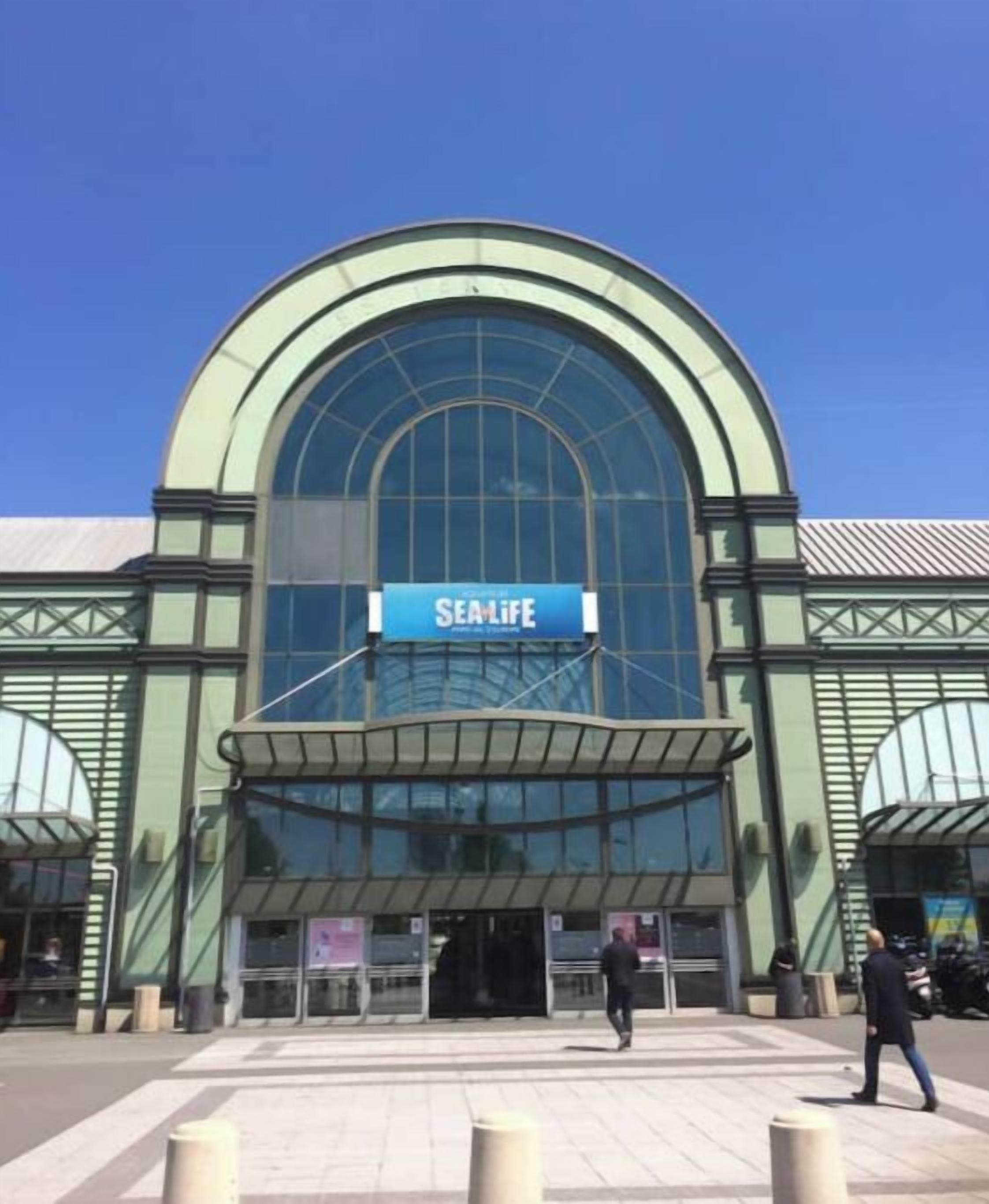 Un edificio moderno con una amplia entrada arqueada y un letrero que dice "SEAM LIFE".