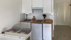 A compact kitchen with white cabinets, a small sink, a dishwasher, and a wooden countertop. - Disney cocooning 5 minutes from the Park (Coupvray)