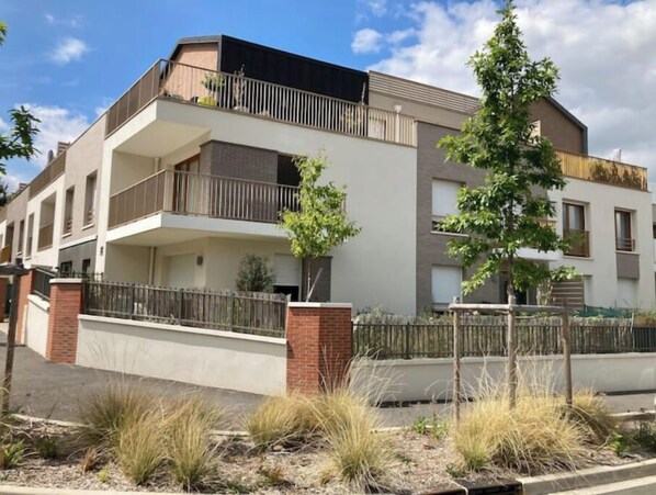 Un edificio residencial moderno de dos pisos con techo plano, balcones y base de ladrillo.