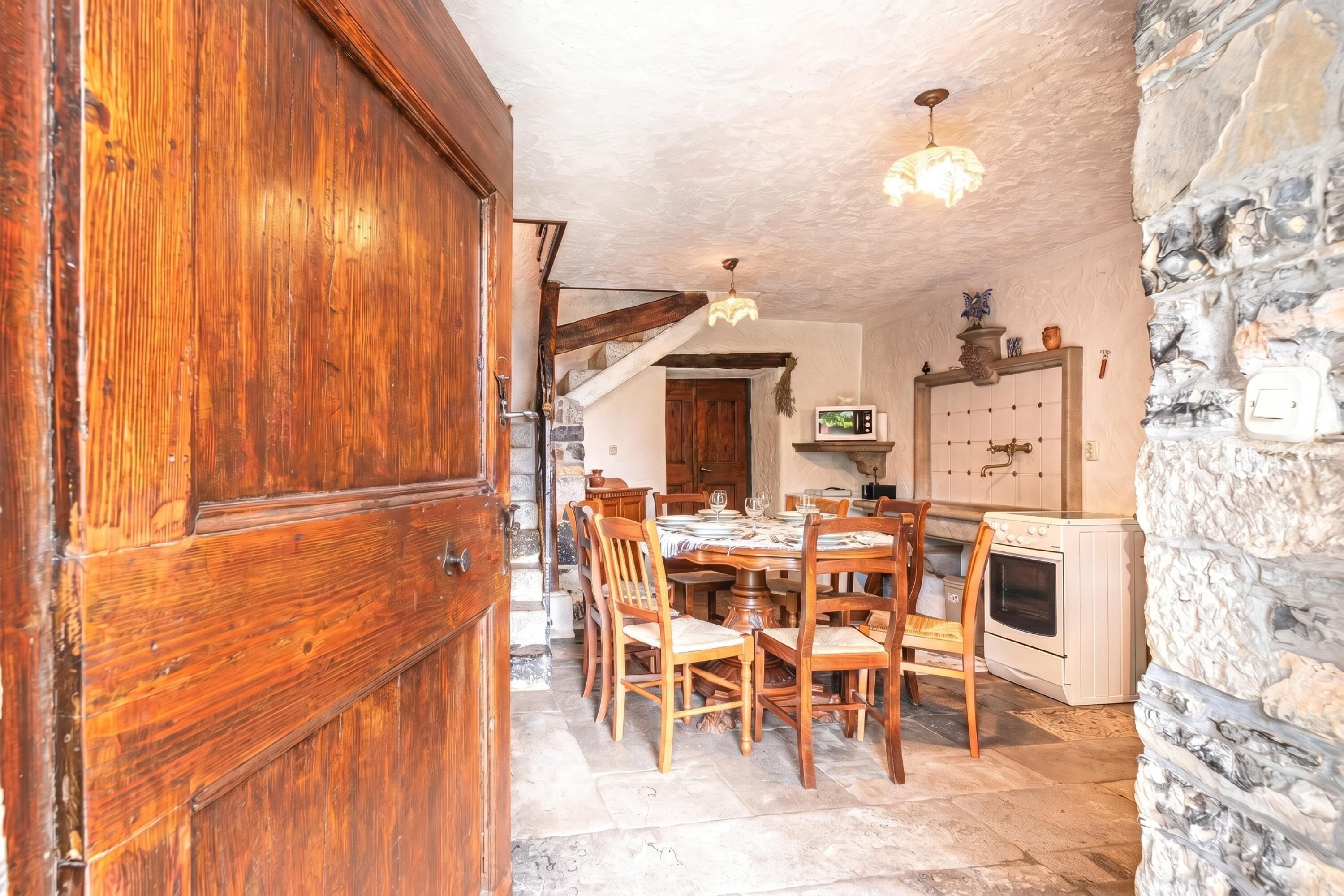 A rustic kitchen with wooden furniture, a stone wall, and a white oven.