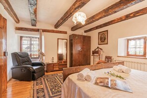 A bedroom with a bed, a recliner, a wardrobe, a mirror, and a window. - Luin Country House Near Stanjel (Komen)