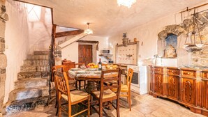 A rustic kitchen with stone walls, wooden furniture, and a stone staircase. - Luin Country House Near Stanjel (Komen)