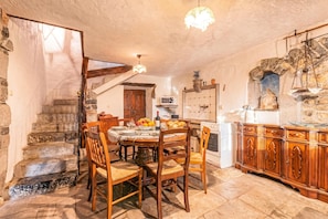 A rustic kitchen with stone walls, wooden furniture, and a stone staircase. - Rustic House Luin (Komen)