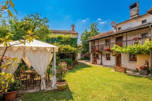 A courtyard with a tent, potted plants, and a table with chairs.