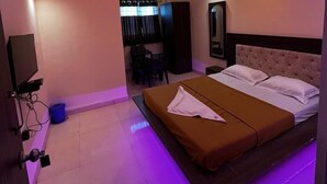Un dormitorio moderno con una cama, ventilador de techo e iluminación LED púrpura.