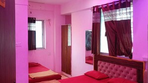 Una habitación con dos camas, ventilador de techo, ventana con cortinas y una puerta.