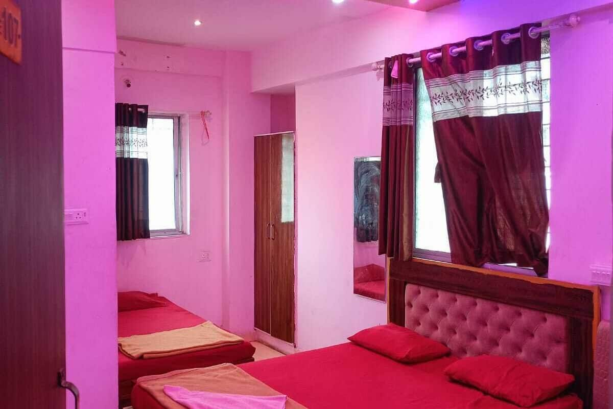 Ein Zimmer mit zwei Betten, einem Deckenventilator, einem Fenster mit Vorhängen und einer Tür.