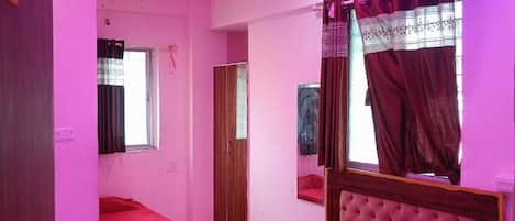 A room with two beds, a ceiling fan, a window with curtains, and a door.