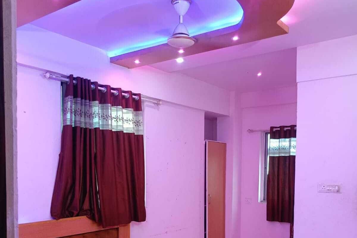 Ein Schlafzimmer mit einem Bett, einem Deckenventilator und einem Fenster mit Vorhängen.