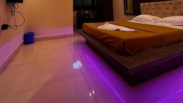 Un dormitorio moderno con cama, ventilador de techo e iluminación ambiental.