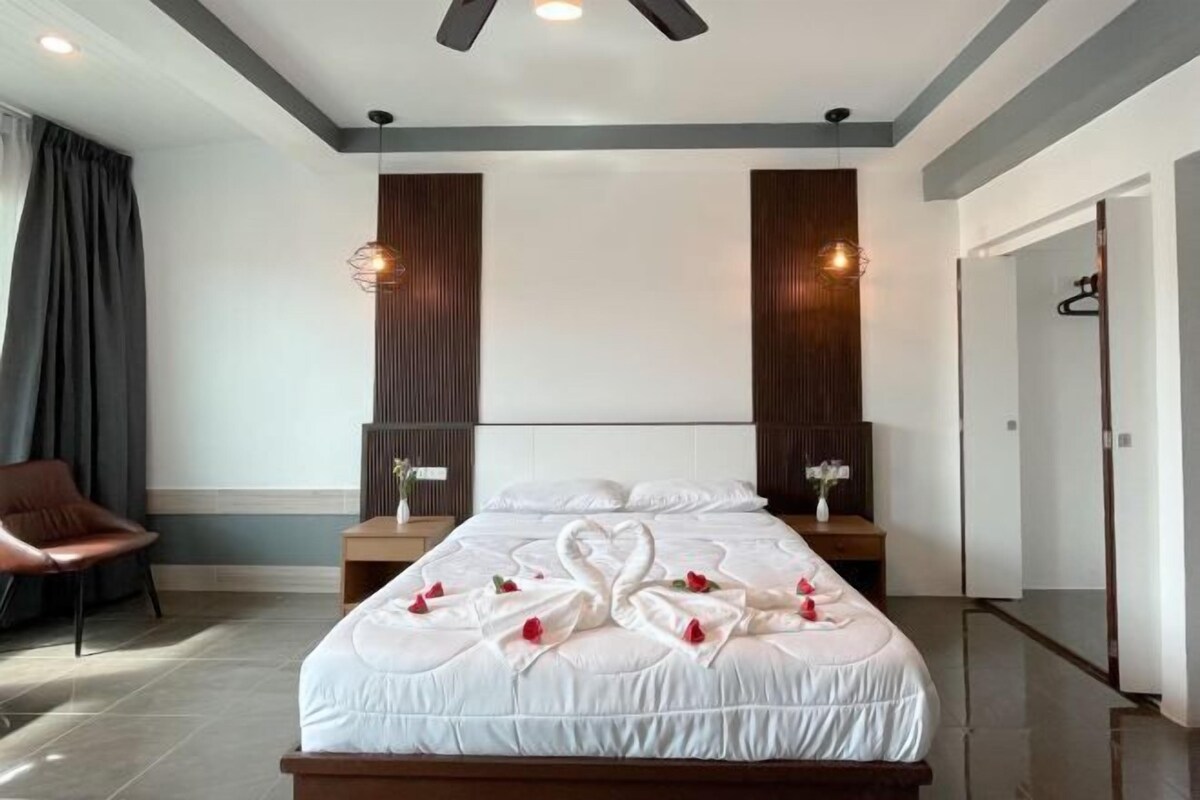 Une chambre d’hôtel moderne avec un grand lit, deux tables de chevet, une chaise et une armoire.