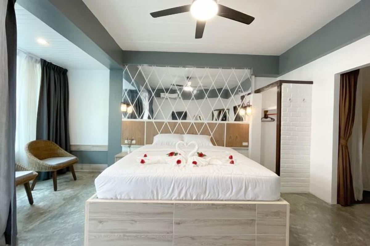 Une chambre à coucher avec un lit, un ventilateur de plafond, une chaise et une armoire.