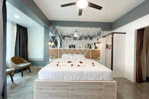A bedroom with a bed, a ceiling fan, a chair, and a wardrobe. - Le Cartier (Phuket)