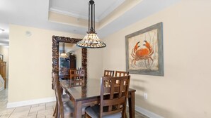 Un coin repas avec une table et des chaises en bois, un luminaire décoratif suspendu et une œuvre d’art encadrée au mur.