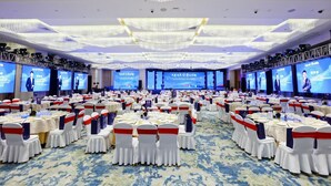 A large conference room with rows of tables and chairs, digital screens, and a chandelier. - HALCYONBOWER INTERNATIONAL HOTEL (Quanzhou)
