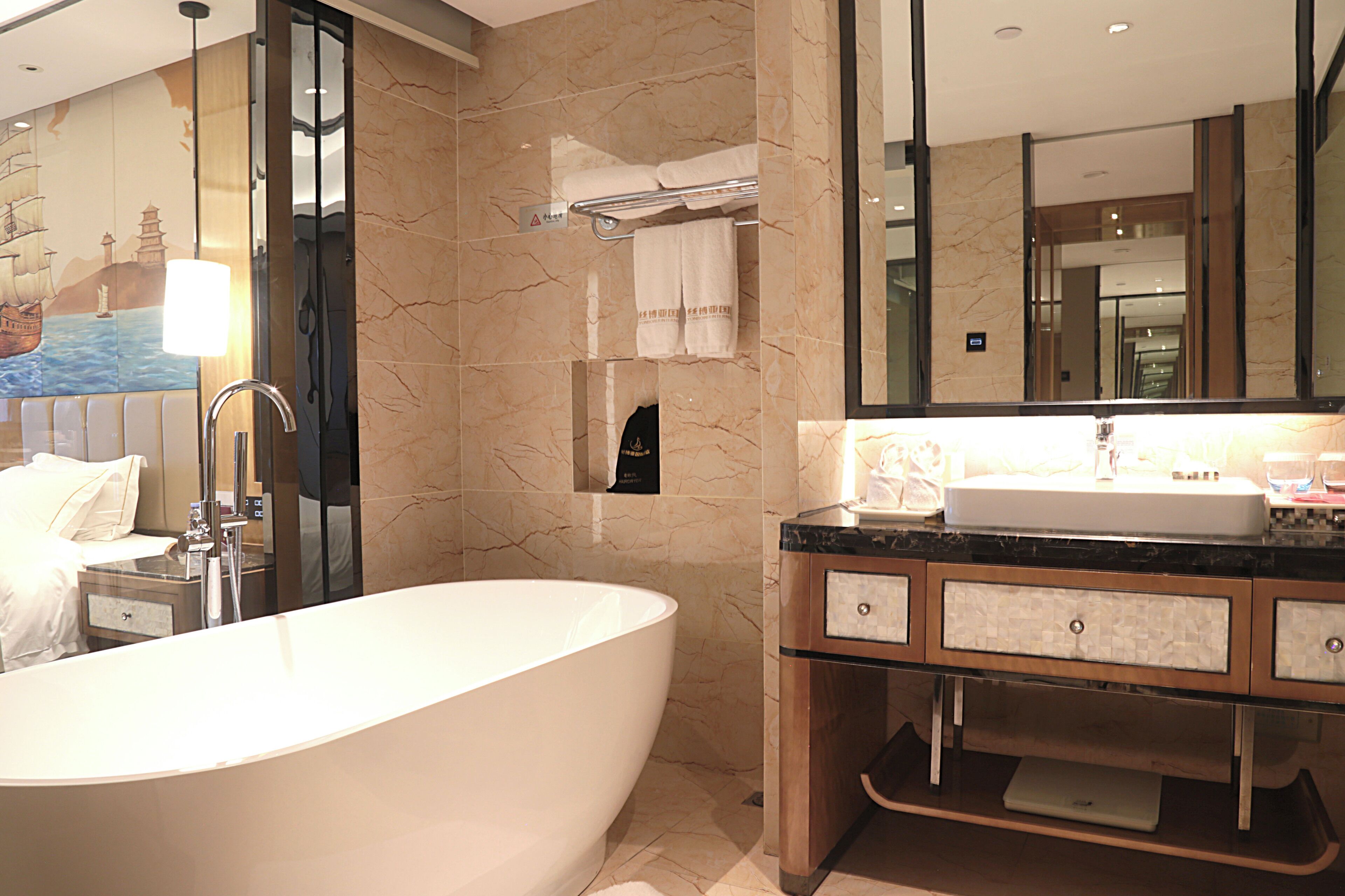 Une salle de bain moderne avec une baignoire sur pieds, un meuble-lavabo avec un miroir et un porte-serviettes.