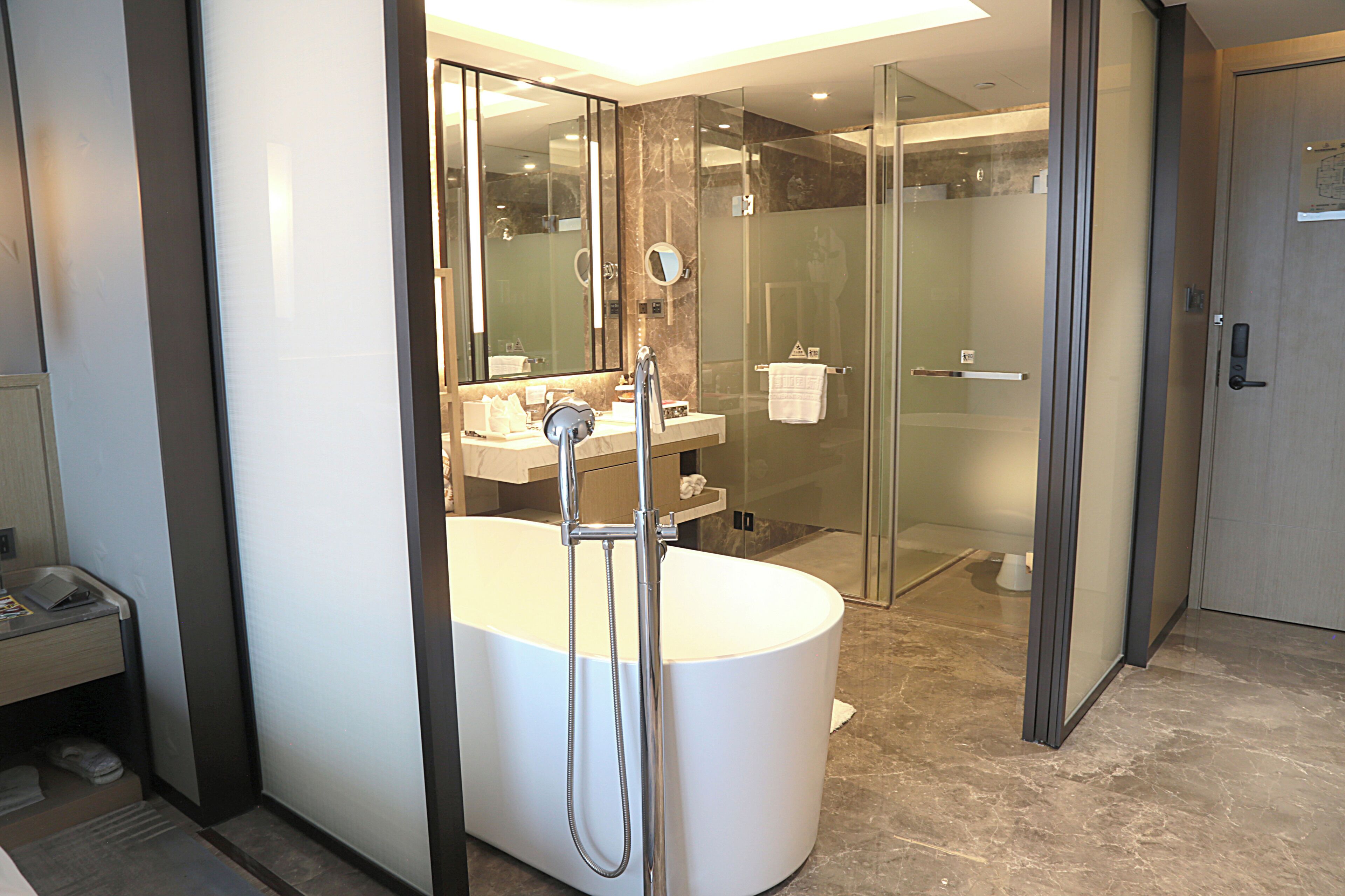 Un baño moderno con una bañera grande, una ducha con cerramiento de vidrio y un tocador con espejo.