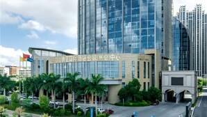 A modern high-rise building with a curved facade, surrounded by palm trees and a clear sky. - HALCYONBOWER INTERNATIONAL HOTEL (Quanzhou)