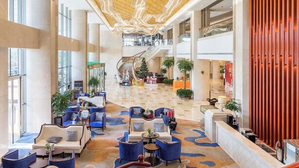 A spacious lobby with a high ceiling, a central staircase, and seating areas. - HALCYONBOWER INTERNATIONAL HOTEL (Quanzhou)