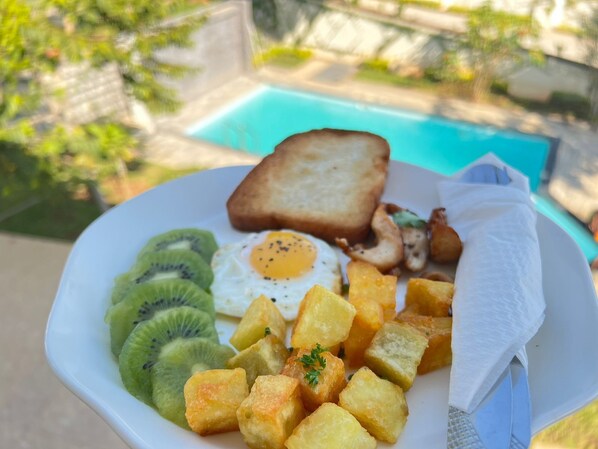Ein Frühstücksteller mit Toast, Spiegelei, Kiwischeiben und Bratkartoffeln.
