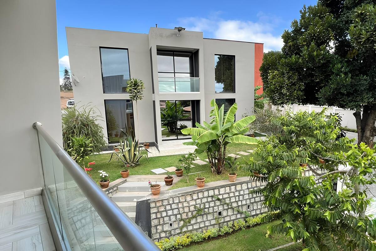 A modern building with large windows and a well-maintained garden with potted plants and a stone wall.