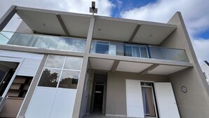 Un edificio moderno de dos pisos con techo plano, ventanas grandes y vestíbulo cubierto.