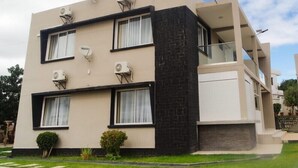 Un edificio moderno de dos plantas con techo plano, ventanas grandes y unidades de aire acondicionado en el exterior.