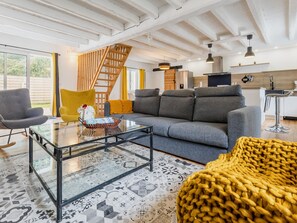 Ein modernes Wohnzimmer mit einem Glastisch, einer Couch, einem gelben Sessel und einer Treppe.