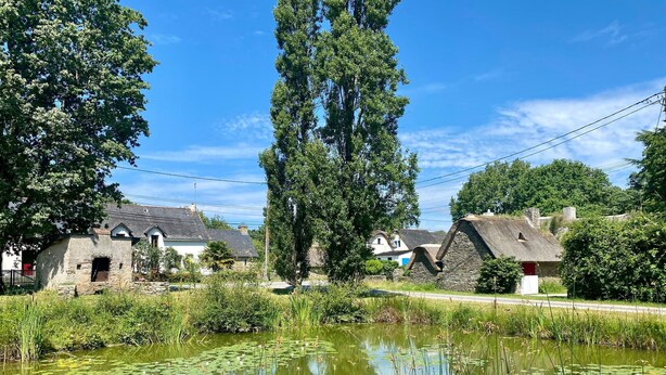 A rural village with stone houses, a pond with lily pads, and tall trees. - Charming Cottage with Terrace, Near Beaches, Parking, Wi-Fi, Baby Equipment, and Ping-Pong (Saint-Lyphard)