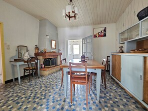 Ein Essbereich mit Schachbrettmuster-Boden, einem Holztisch und Stühlen. Ein Kamin mit einem Spiegel darüber.