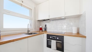 A modern kitchen with white cabinets, a stainless steel sink, a built-in oven, and a window above the sink. - 2-Bedroom Apartment with Beach Access & Private Parking (Roses)