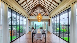 Una habitación amplia con una larga mesa y sillas, ventanas grandes y techo de madera.