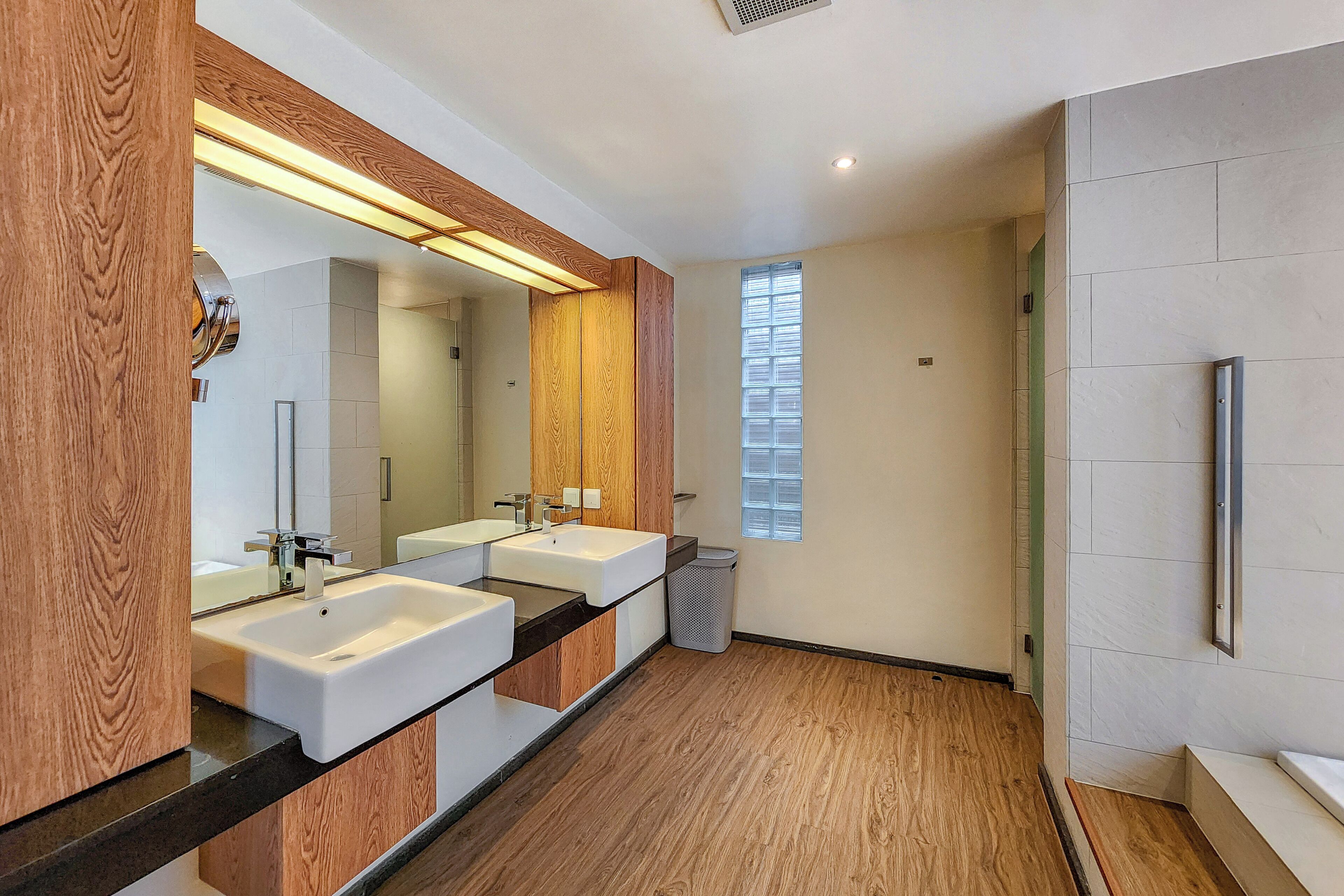 Un baño moderno con dos lavamanos, paneles de madera y un espejo grande.