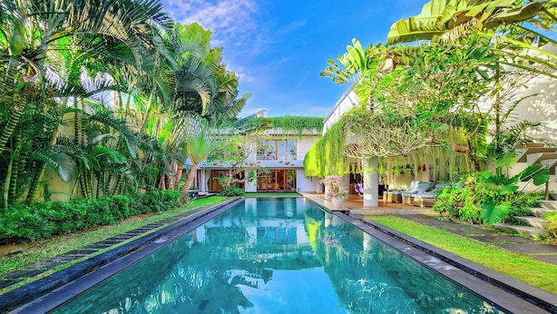 Una piscina rodeada de exuberante vegetación y un edificio con fachada de vidrio.