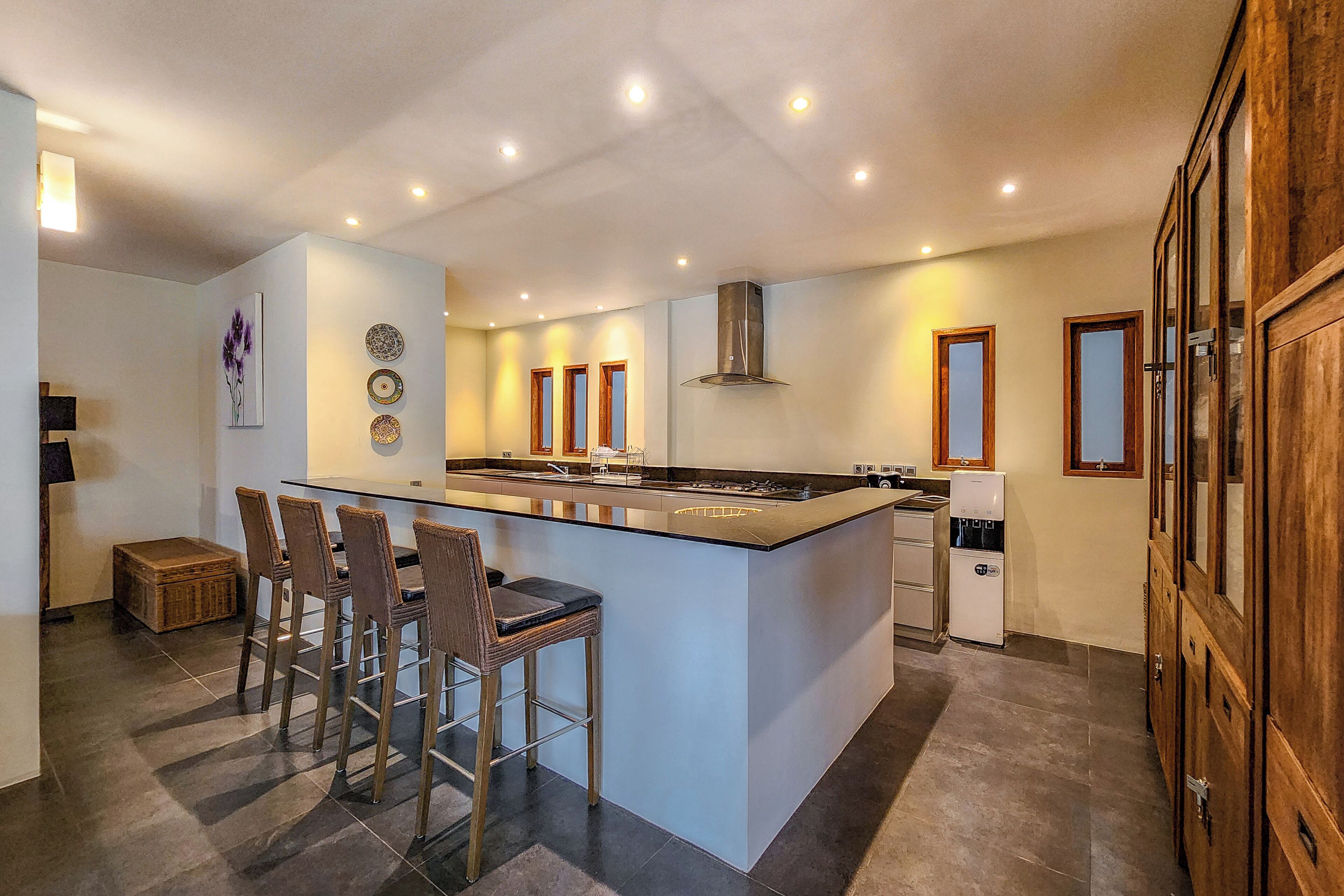 A modern kitchen with a central island, bar stools, and a refrigerator.